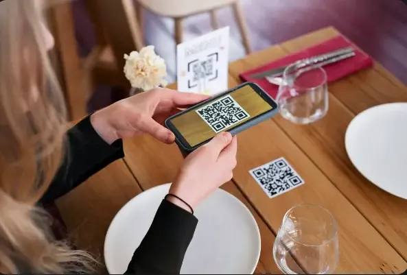 Customer using a smartphone to scan a QR code at a hotel restaurant, enabling digital menu access, contactless ordering, and a seamless guest dining experience.