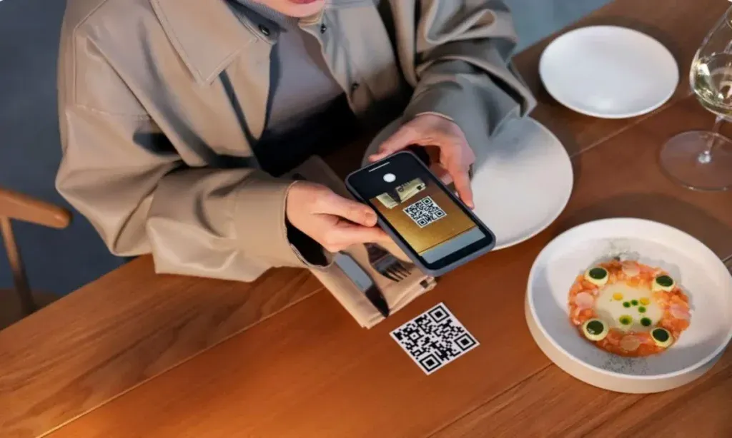 Guest scanning a QR code on a restaurant table using smartphone for contactless hotel food ordering and digital menu access.
