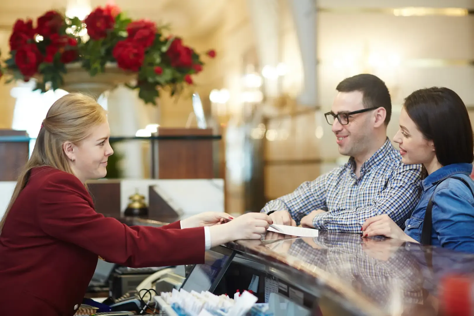 Hotel front desk staff assisting guests during check-in, showcasing hospitality customer service and efficient hotel reception management.