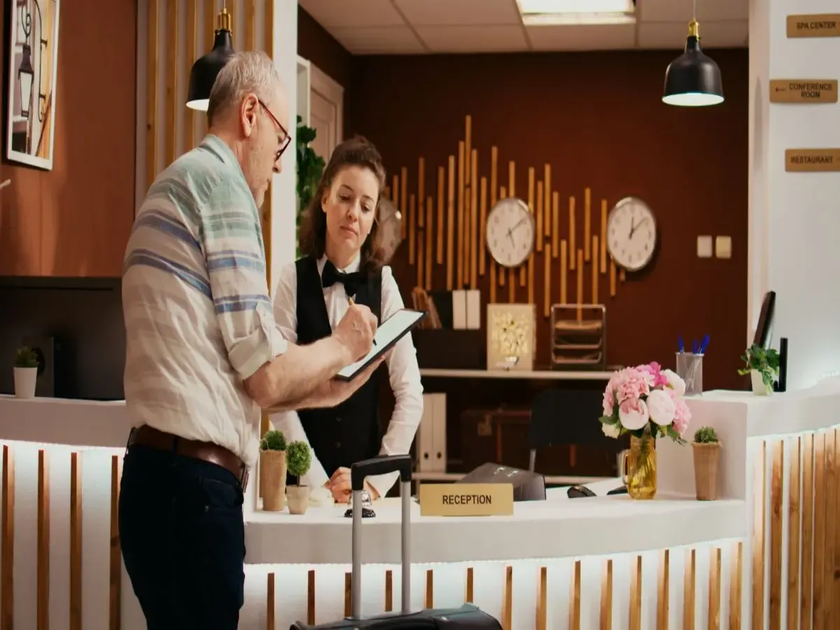 Hotel receptionist assisting a guest with check-in documents at the reception desk