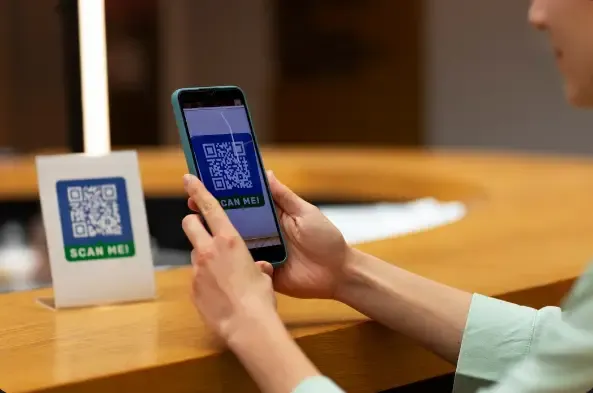 Guest scanning a QR code with a smartphone at a hotel restaurant counter, accessing a digital menu for contactless ordering, faster service, and improved guest convenience.